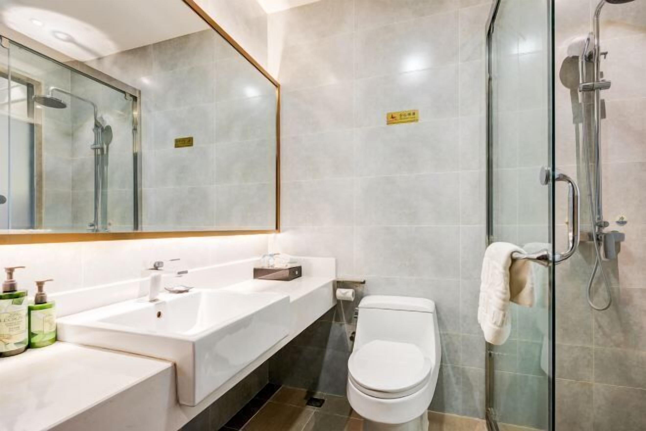 Ein modernes Badezimmer mit einer Duschkabine, einem weißen Waschbecken und einer Toilette.