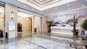 A modern hotel lobby with a marble floor, a reception desk, and decorative lighting.