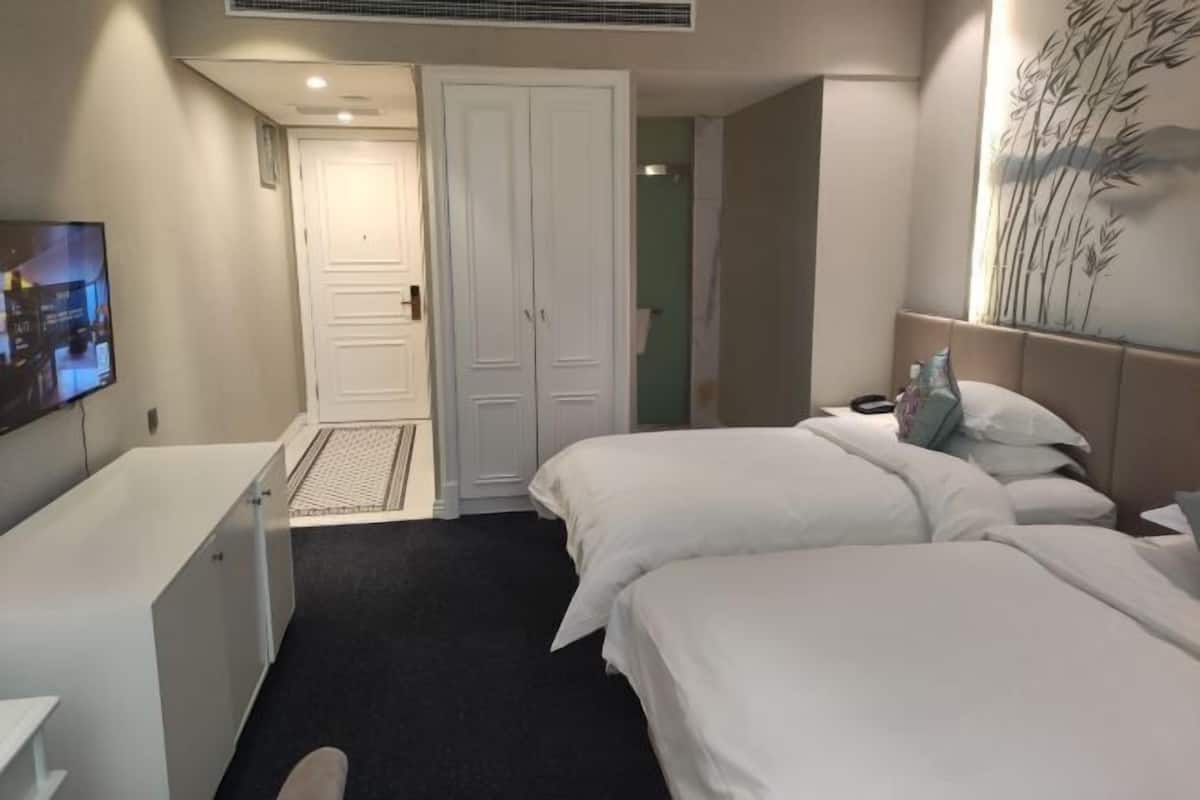 A hotel room with a bed, a desk, and a wardrobe.