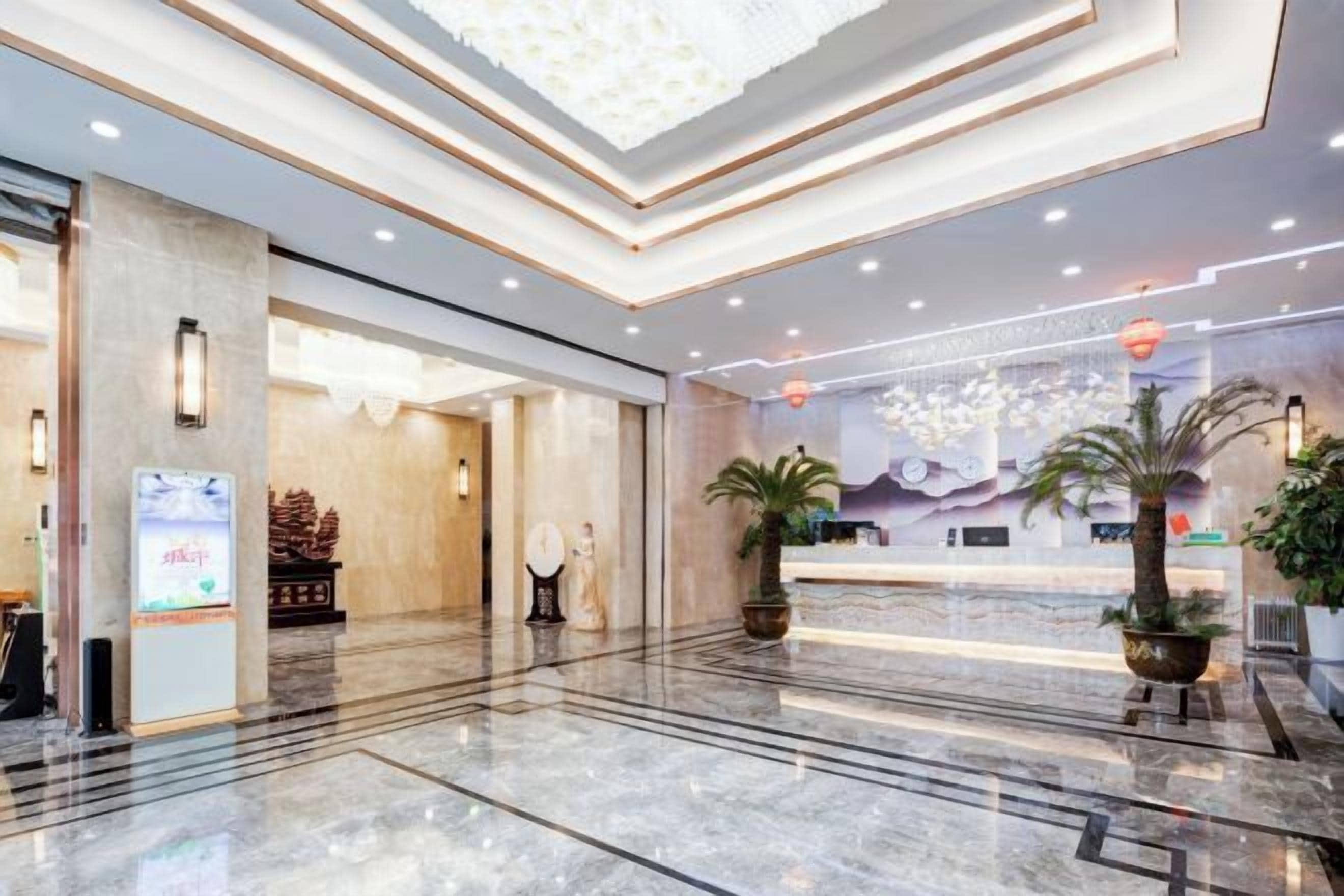 Un vestíbulo de hotel con un mostrador de recepción, una gran araña y un suelo de mármol.