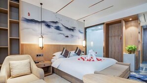 A modern hotel room with a large bed, a seating area, and a wall mural.