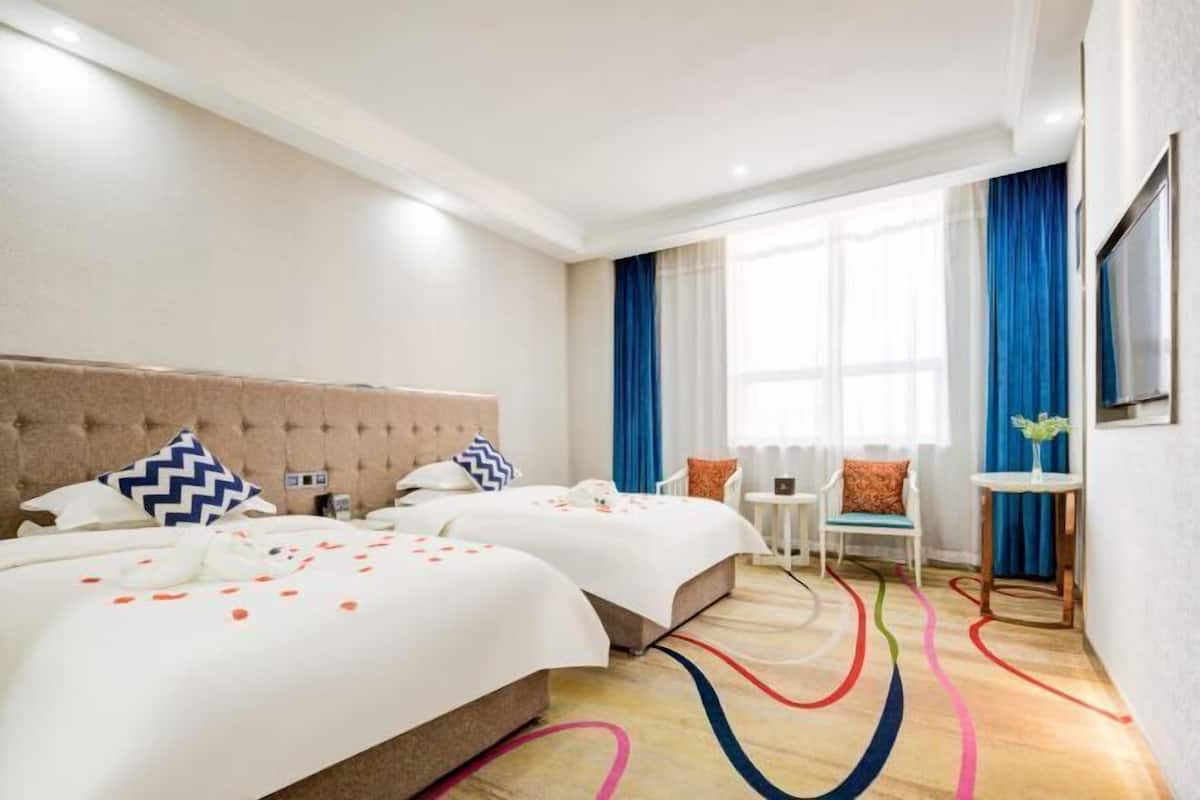 A hotel room with two beds, a small table, and a chair.