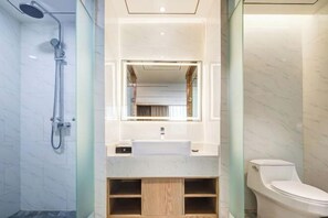 A modern bathroom with a shower, a sink, a toilet, and a mirror. - Jiuzhou International Hotel (Tongchuan)