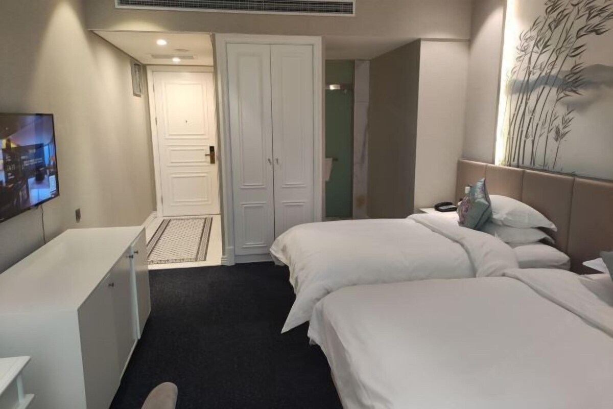 A hotel room with a bed, a desk, and a wardrobe.