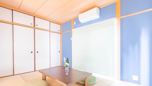 Um quarto japonês tradicional com tatames, uma mesa de madeira baixa e um porta deslizante.