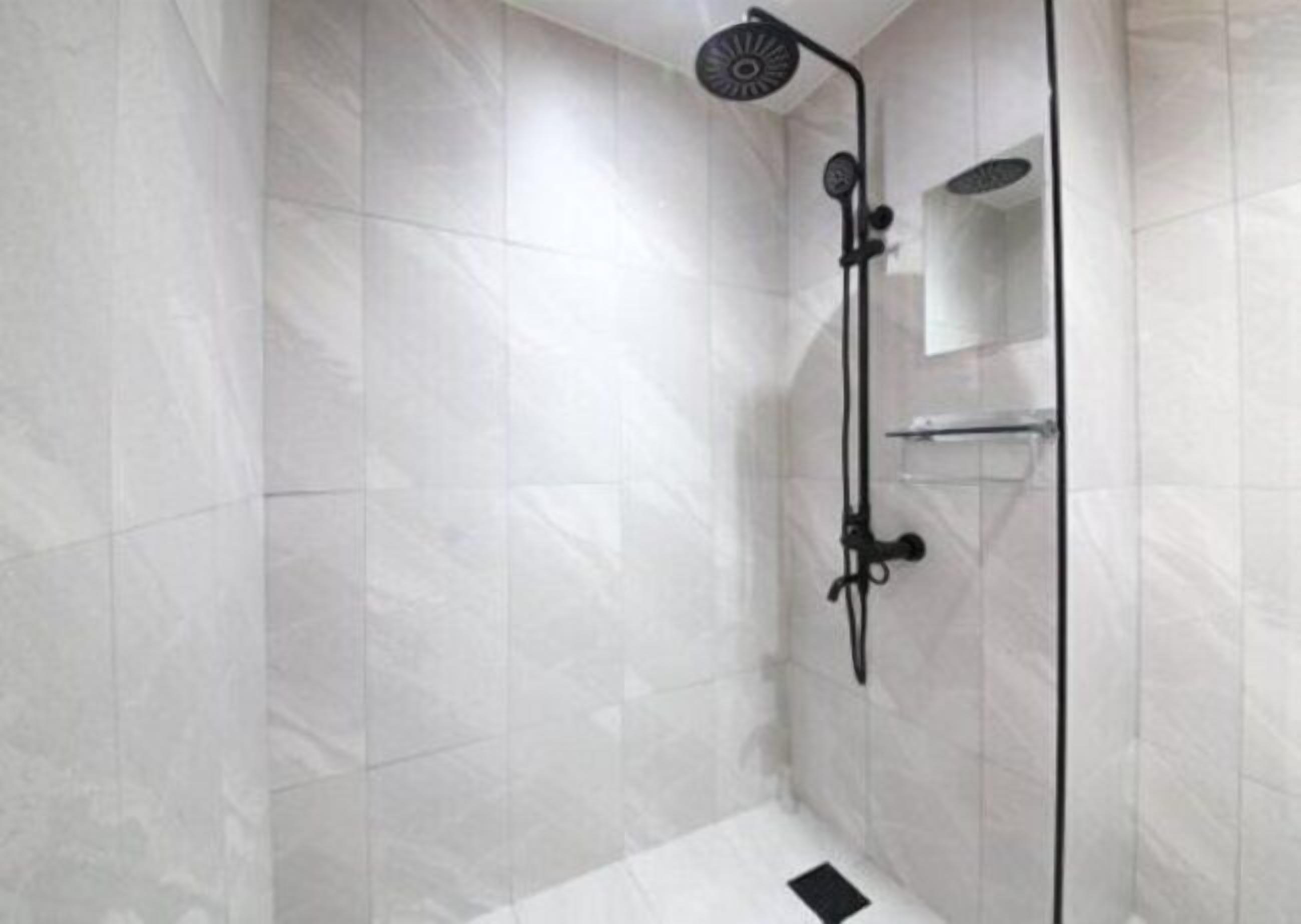 A modern shower with a handheld showerhead and a wall-mounted control panel.
