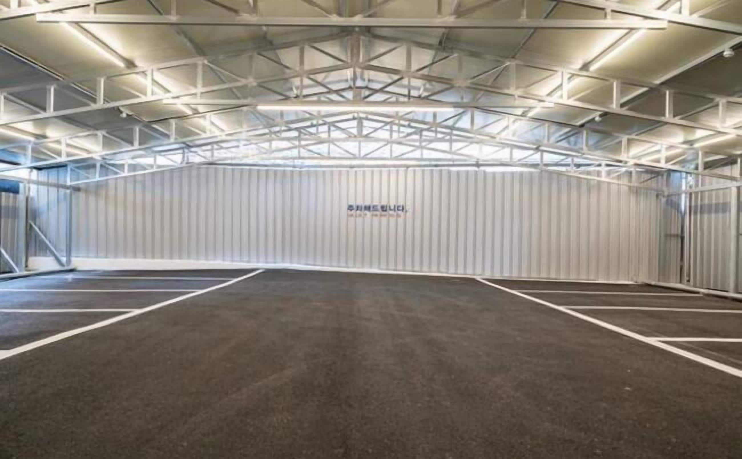 Instalación deportiva interior con techo alto y una pared central que muestra el texto 
