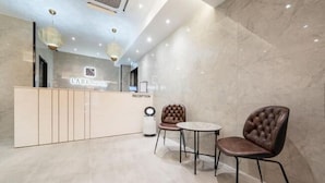 A reception area with a reception desk, two chairs, and a trash bin. - LABE Hotel (Jeonju)