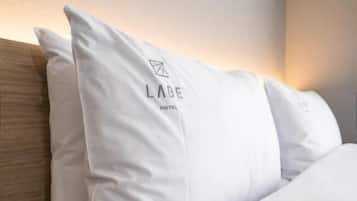 Letto d'albergo con cuscini bianchi e il logo dell'Hotel Labe.