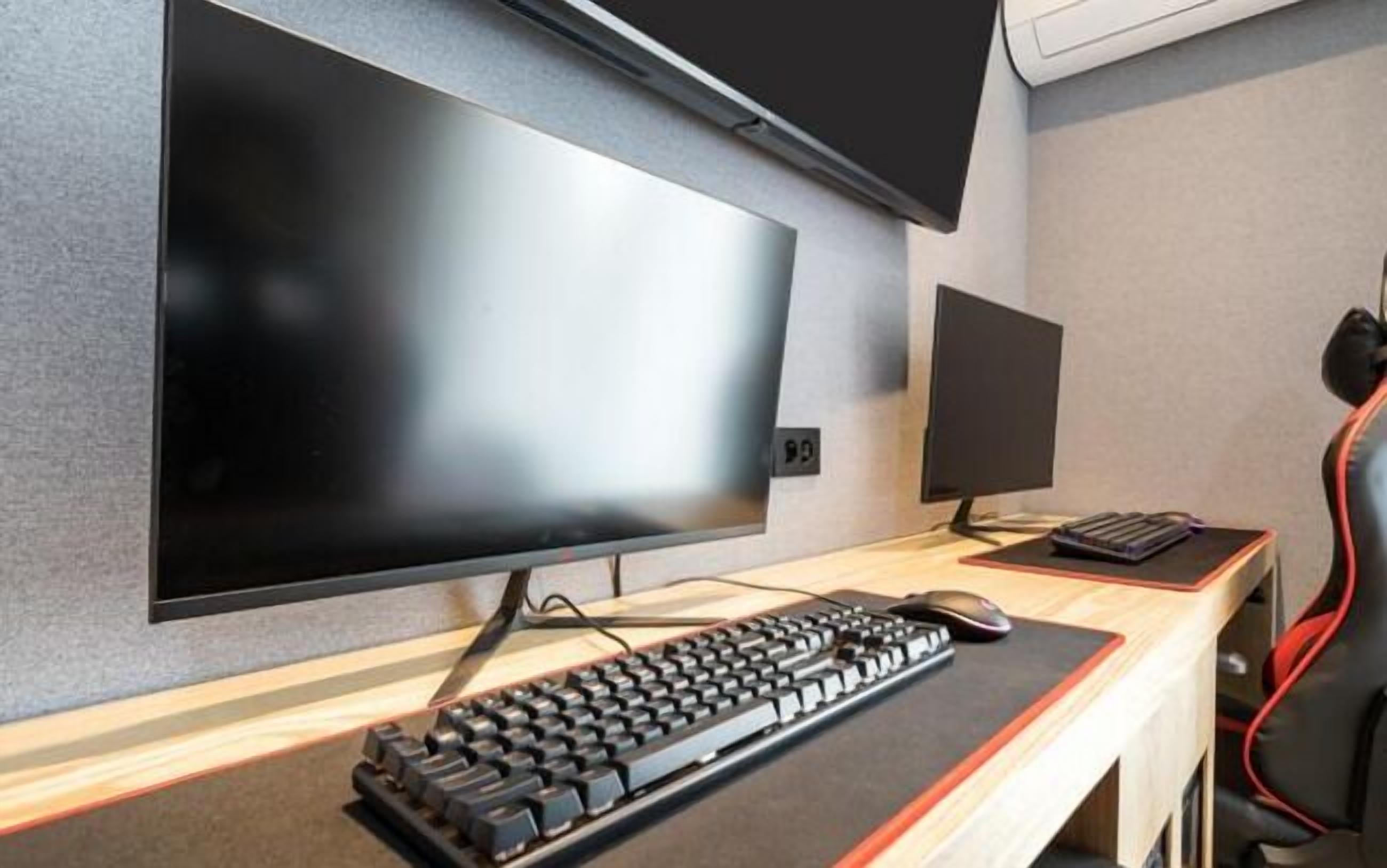 A modern office setup with a large flat-screen monitor, a smaller monitor, a keyboard, and a mouse on a desk.