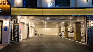 A parking garage entrance with multiple parking spaces, illuminated ceiling lights, and a sign indicating the garage is open. - LABE Hotel (Jeonju)