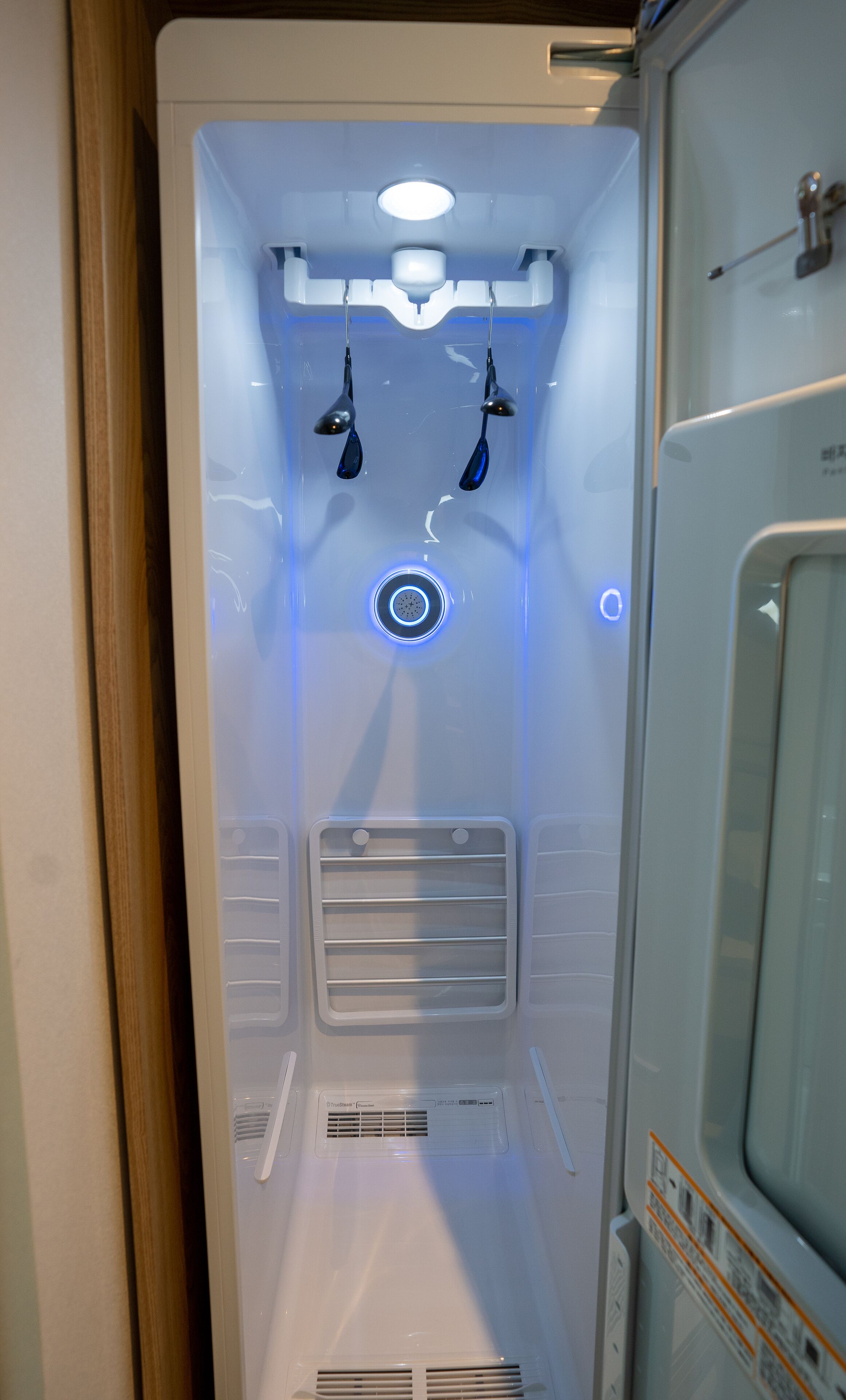 A compact, modern room with a built-in shower, a control panel, and a ventilation system.