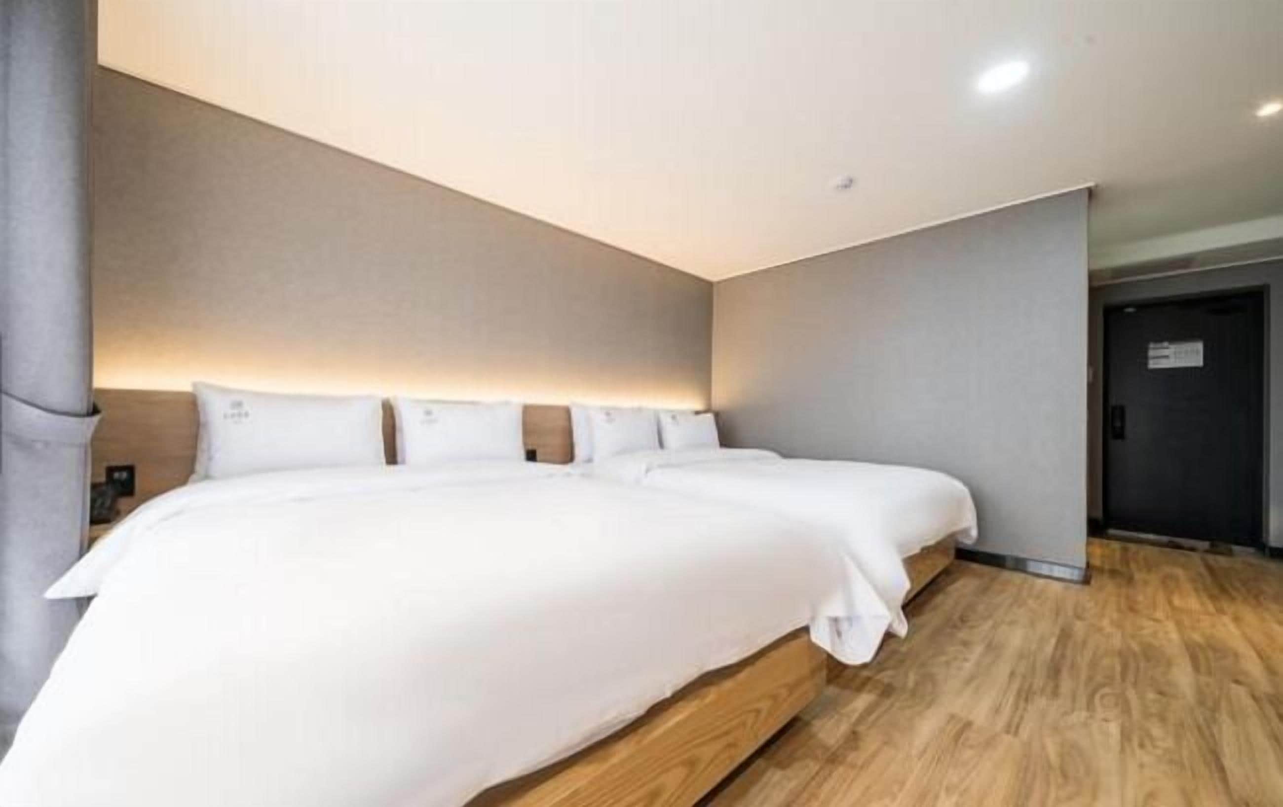 Een moderne hotelkamer met een groot bed, houten vloeren en een neutrale kleurenschema.