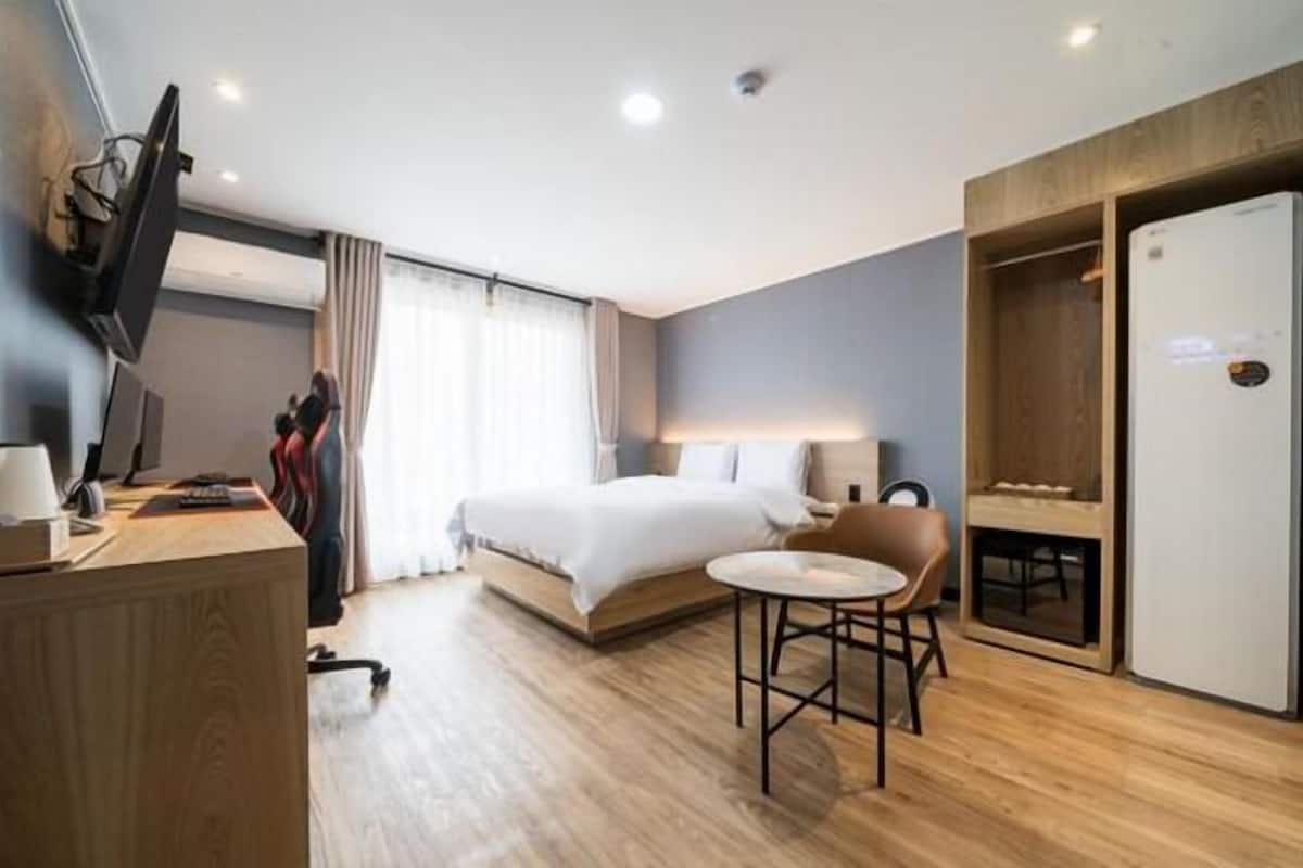 Una habitación de hotel moderna con cama, escritorio, silla y armario.