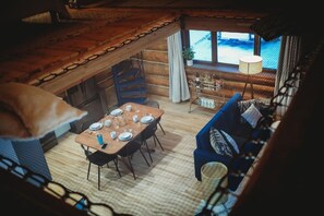 Una habitación acogedora de estilo cabaña con zona de comedor, sofá y ventana con vistas a un paisaje nevado.