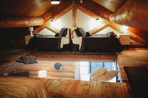 A cozy attic bedroom with a loft bed, wooden beams, and a skylight.