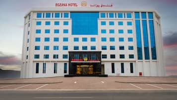 Welcome to the Rozana Hotel, featuring a symmetrical facade with a prominent entrance and parking area.