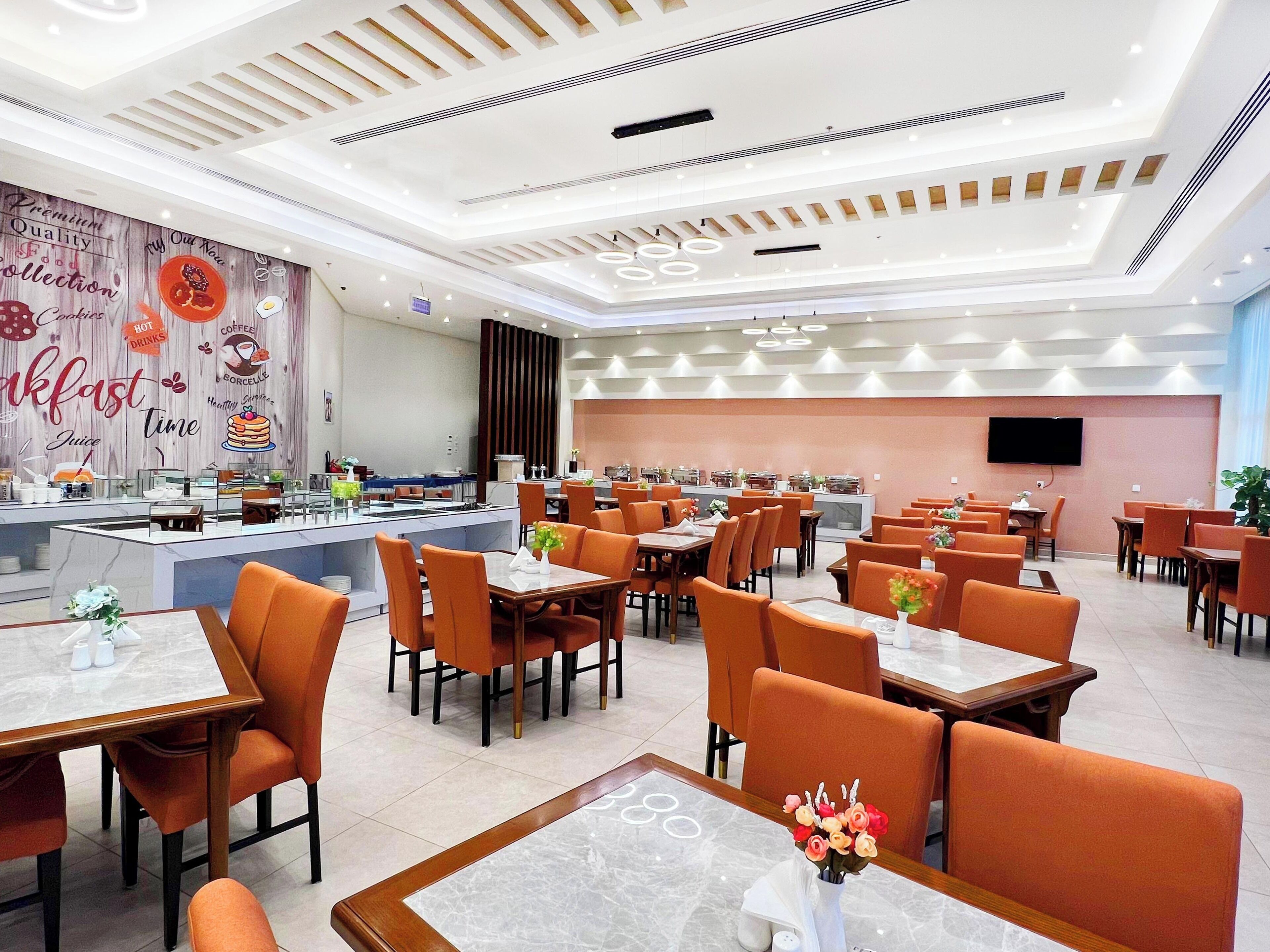 Un restaurante moderno con barra para desayuno, sillas color naranja y diversas mesas de comedor.