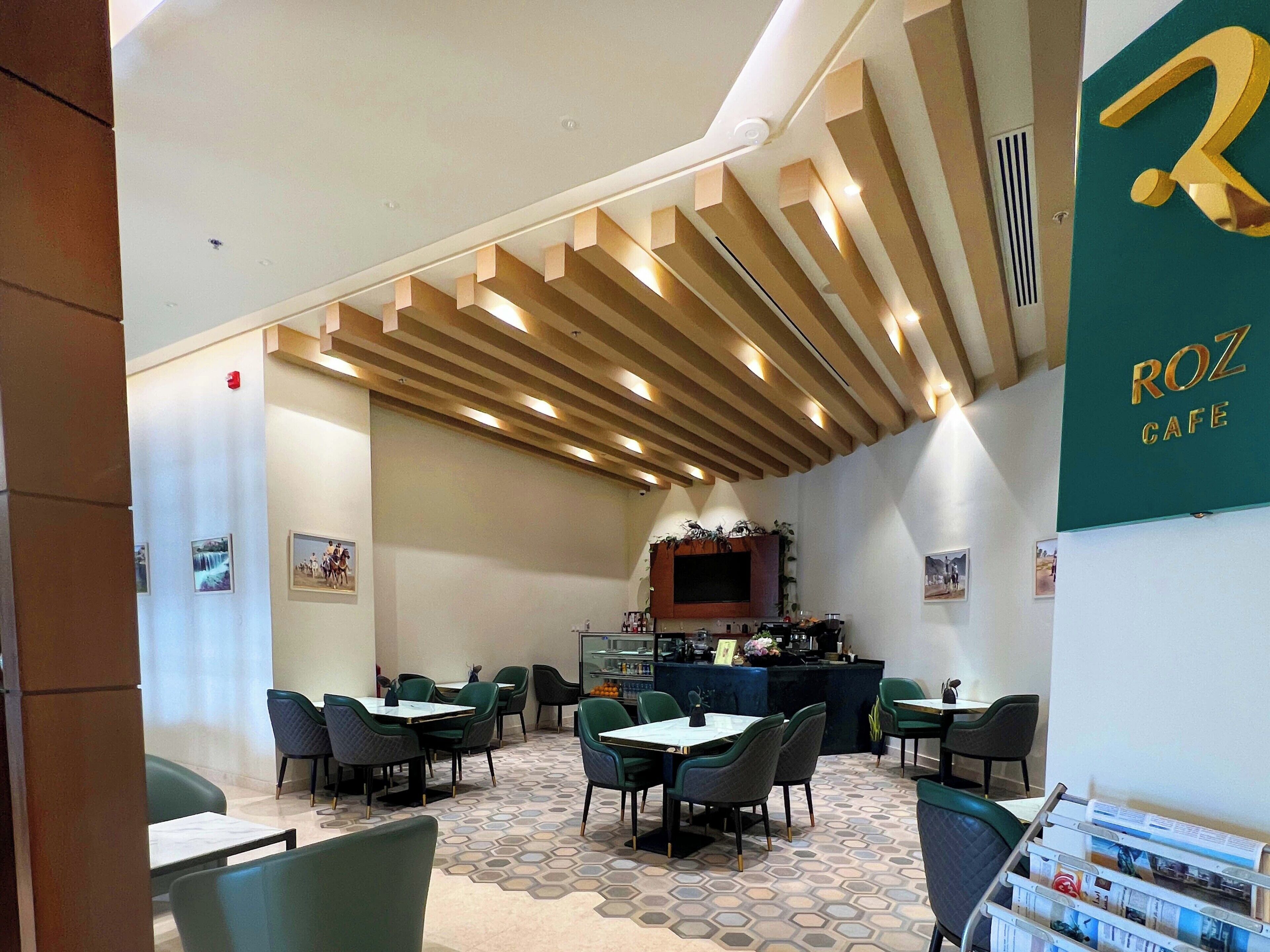 A cafe with a modern interior, featuring a counter, seating area, and a decorative ceiling.