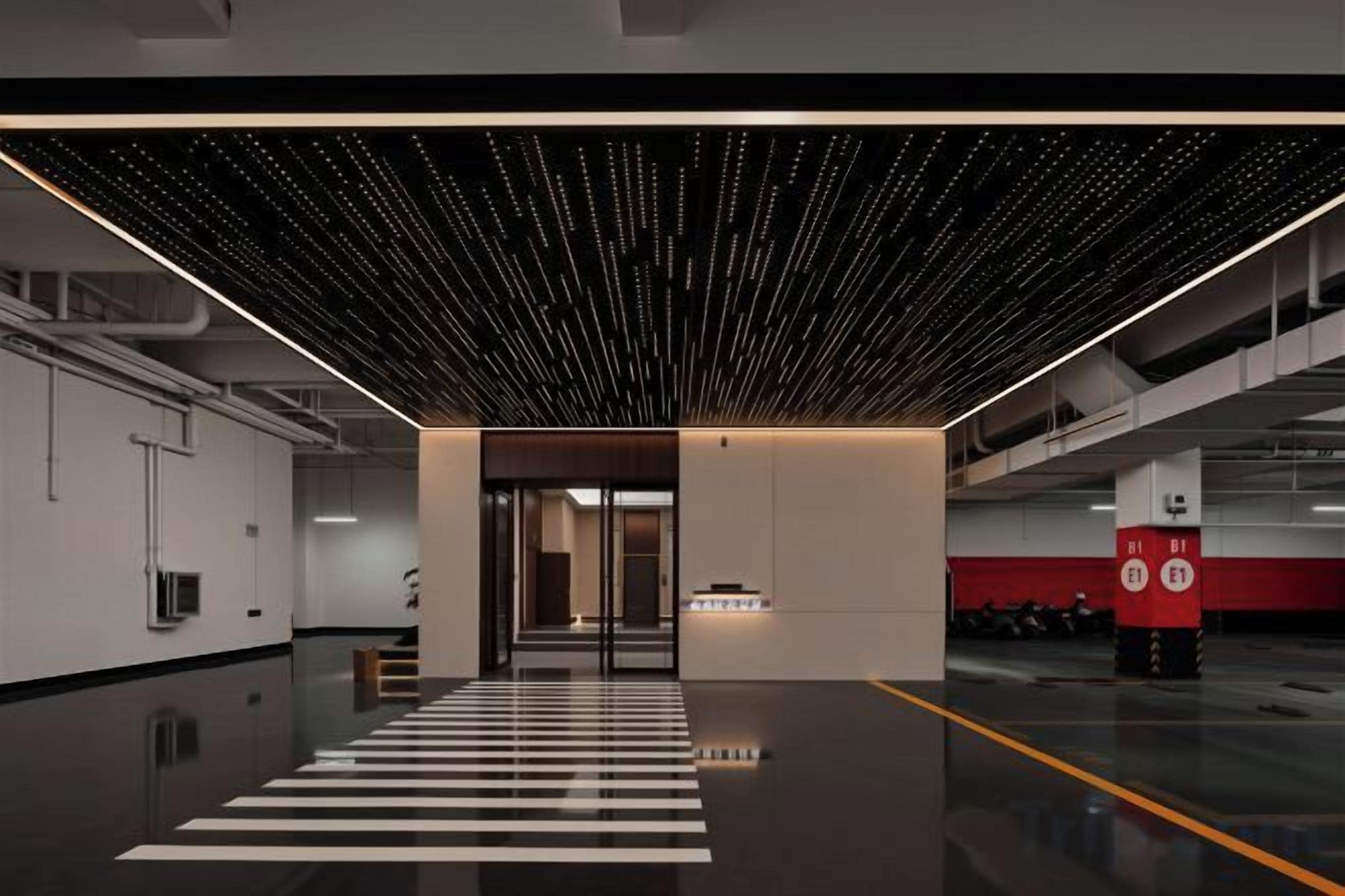 A modern interior with a reflective floor, a patterned ceiling, and a red and white pillar.