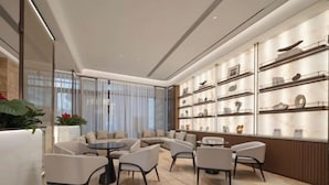 A modern interior with a curved seating area, a wall of decorative items, and a large window with sheer curtains. - Anning Golden Age Hotel (Anning)