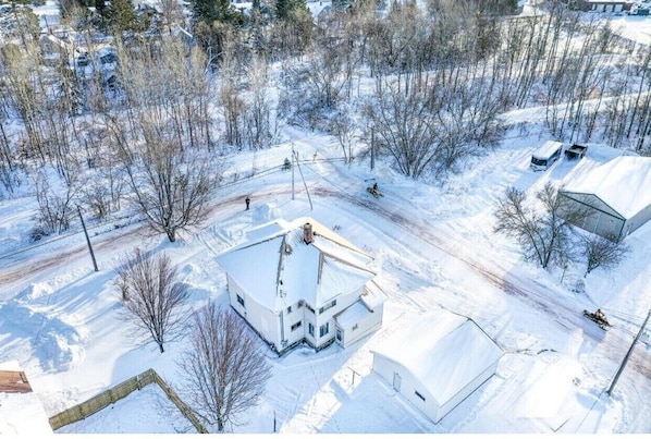 Set amidst a serene winter landscape, this charming two-story house features a gabled roof and a chimney.