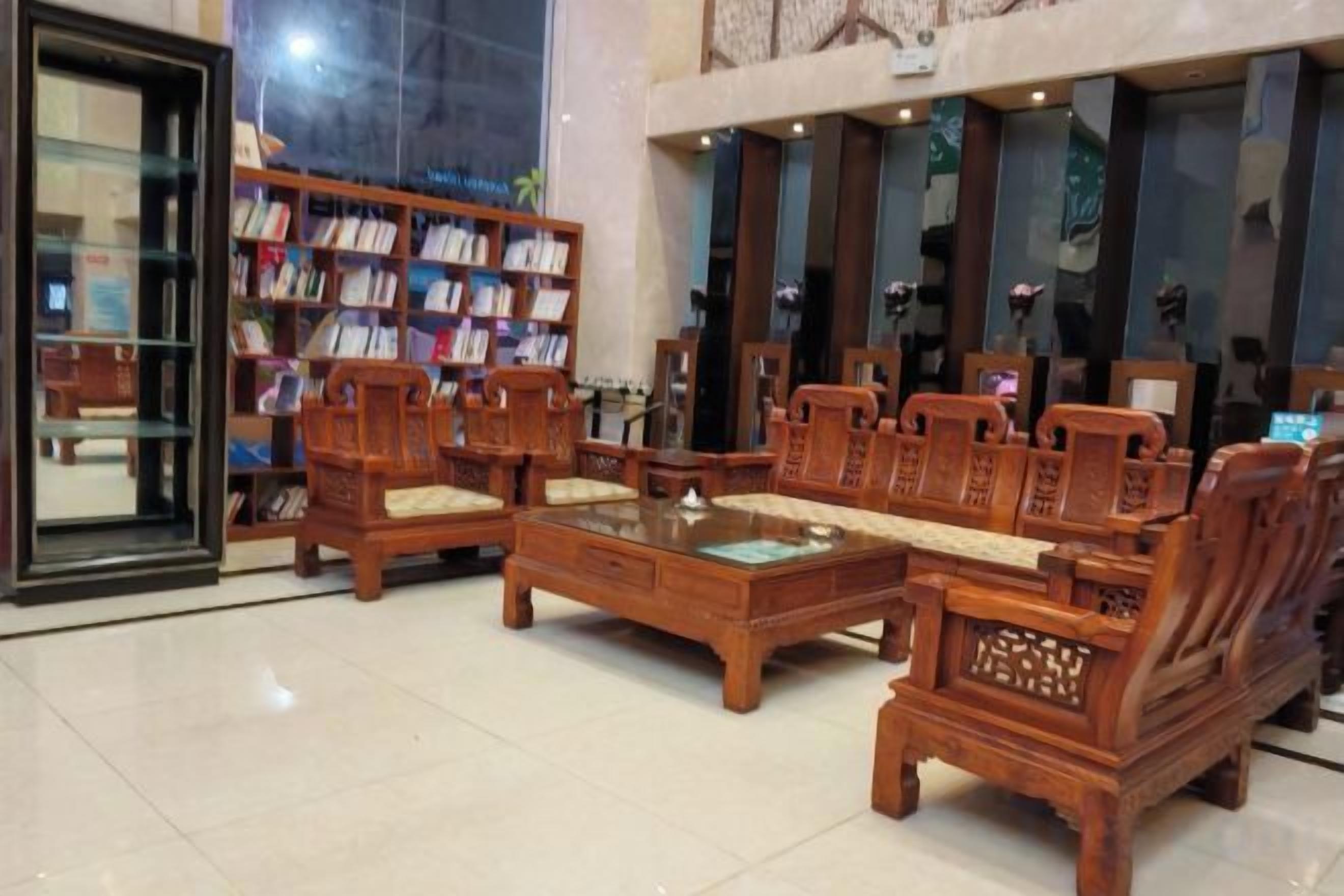 A lobby with a wooden sofa set, a coffee table, and a bookshelf.