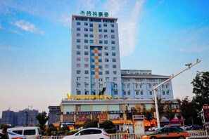 Een meerhoog hotel met een opvallend bord bovenop, verschillende etages met ramen en een gelijkvloers gedeelte met diverse winkels.