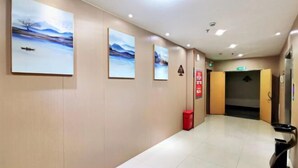 A hotel corridor with artwork on the walls, a fire extinguisher, and an elevator.
