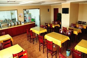 A dining area with multiple tables and chairs, a counter with kitchen equipment, and a television on the wall. - GreenTree Inn (Feng County Liubang Square) (Feng County)