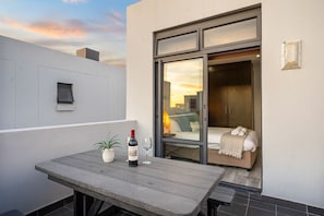 Un espacio al aire libre moderno con una mesa, una botella de vino y una copa.