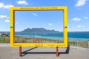 A yellow sign with the text "Table Mountain, Cape Town, South Africa" and coordinates "33°47'30.55" S 18°27'24.15" E".