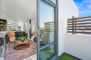 A modern living room with a sofa, coffee table, and a glass door leading to an outdoor balcony.