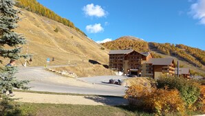 A mountain lodge with multiple balconies, a parking area, and a view of the surrounding hills. - 2 Rooms 35m2 South East view very well equipped (Allos)