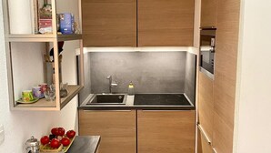 A compact kitchen with wooden cabinets, a built-in sink, and a stove. - 2 Rooms 35m2 South East view very well equipped (Allos)