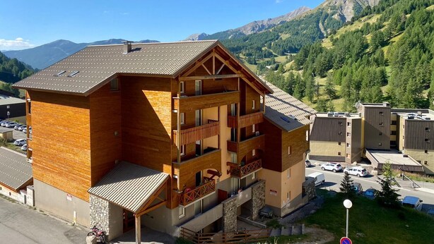 A multi-story wooden building with balconies, set against a mountainous backdrop. - 2 Rooms 35m2 South East view very well equipped (Allos)