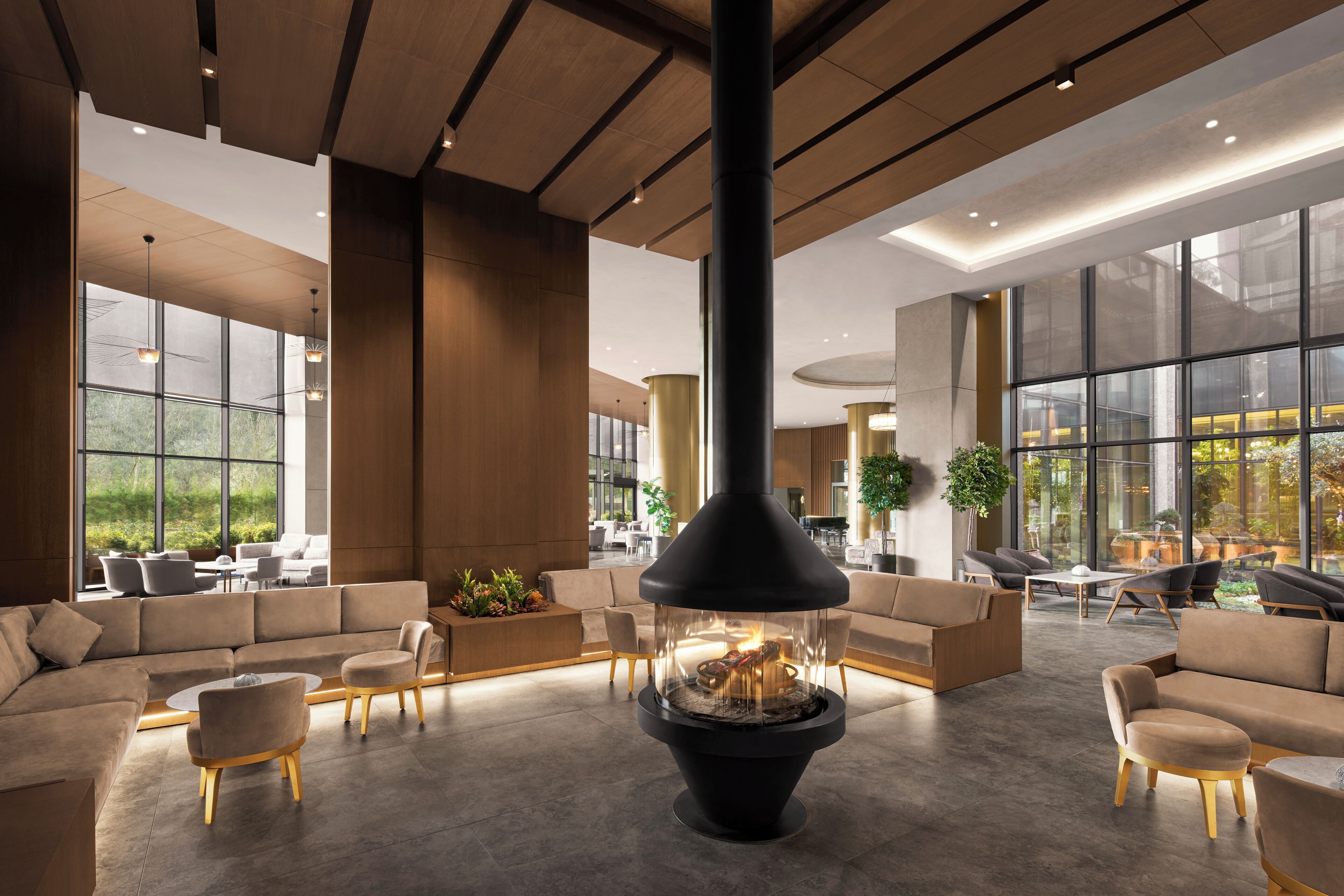 Un área de estar moderna con chimenea central, asientos cómodos y ventanas amplias que ofrecen vistas al exterior.