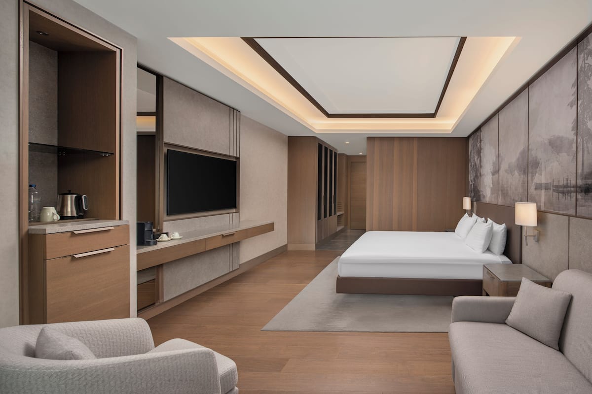 Ein modernes Hotelzimmer mit einem großen Bett, einem Fernseher, einem Schreibtisch und einem Schlafsofa.
