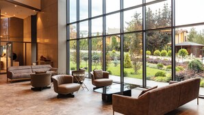 A spacious lobby with large windows, a sofa, armchairs, and a coffee table. - NG Enjoy (Sapanca)