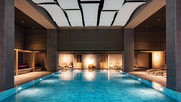 A large indoor swimming pool with a modern design, featuring a central clock, lounge areas, and a ceiling with recessed lighting. - NG Enjoy (Sapanca)