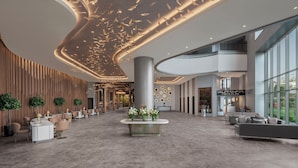A spacious lobby with a central reception desk, seating areas, and a modern ceiling design. - NG Enjoy (Sapanca)
