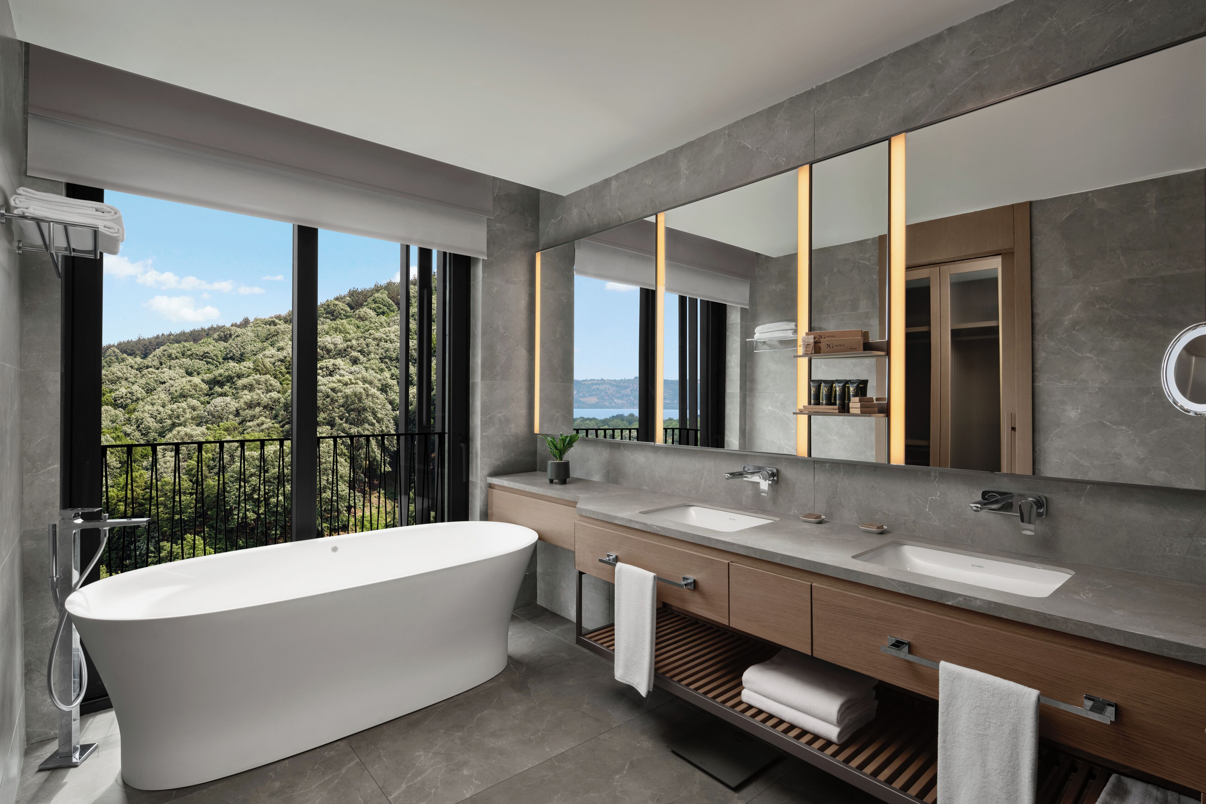 A modern bathroom with a freestanding bathtub, dual sinks, and a large mirror.