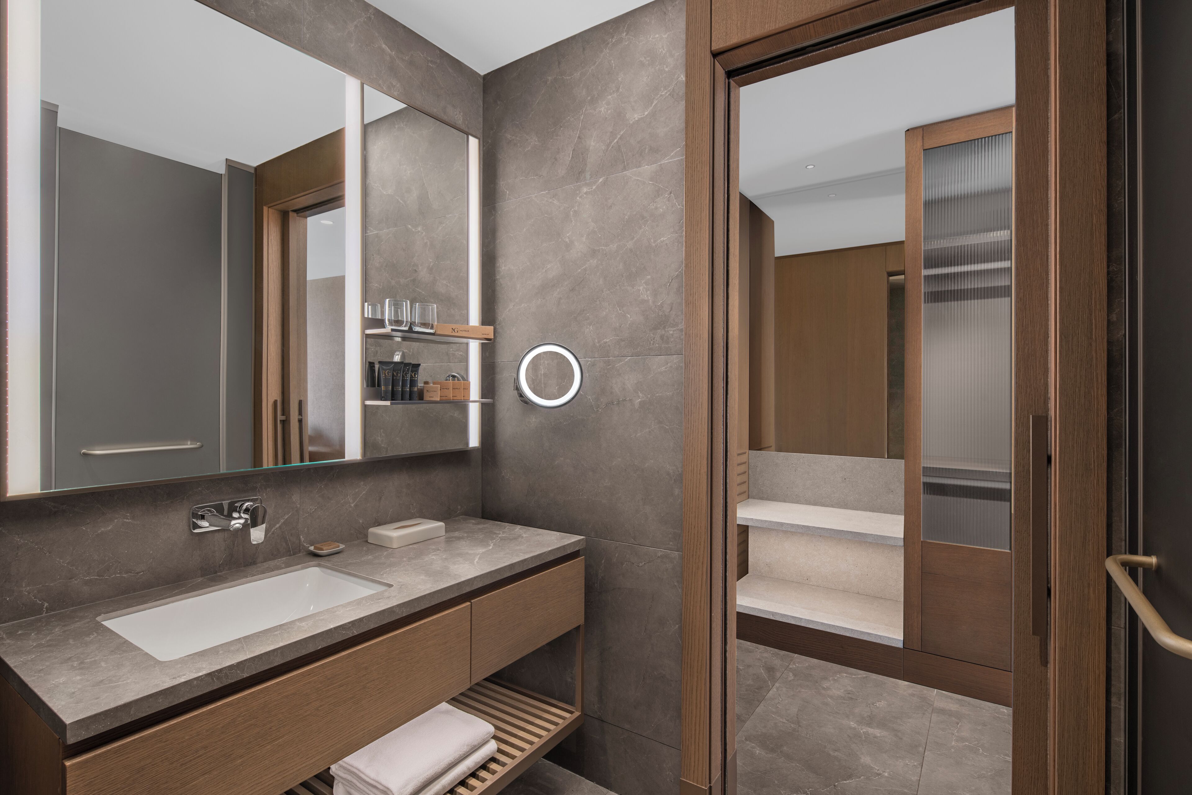 A modern bathroom with a large mirror, a built-in sink, and a vanity with storage.