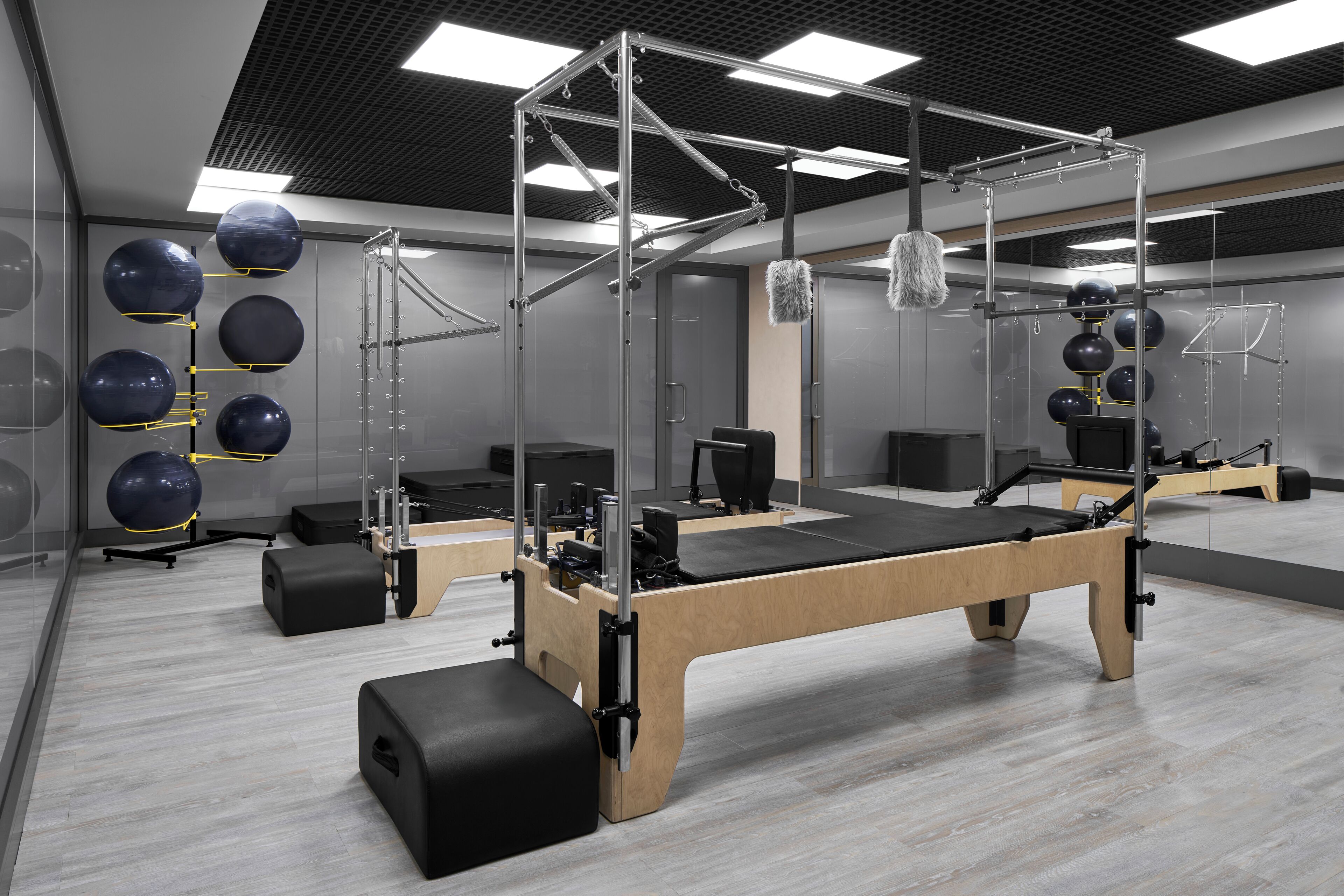 Une salle de sport moderne dotée d’un plancher en bois, d’appareils d’exercice et de murs recouverts de miroirs.