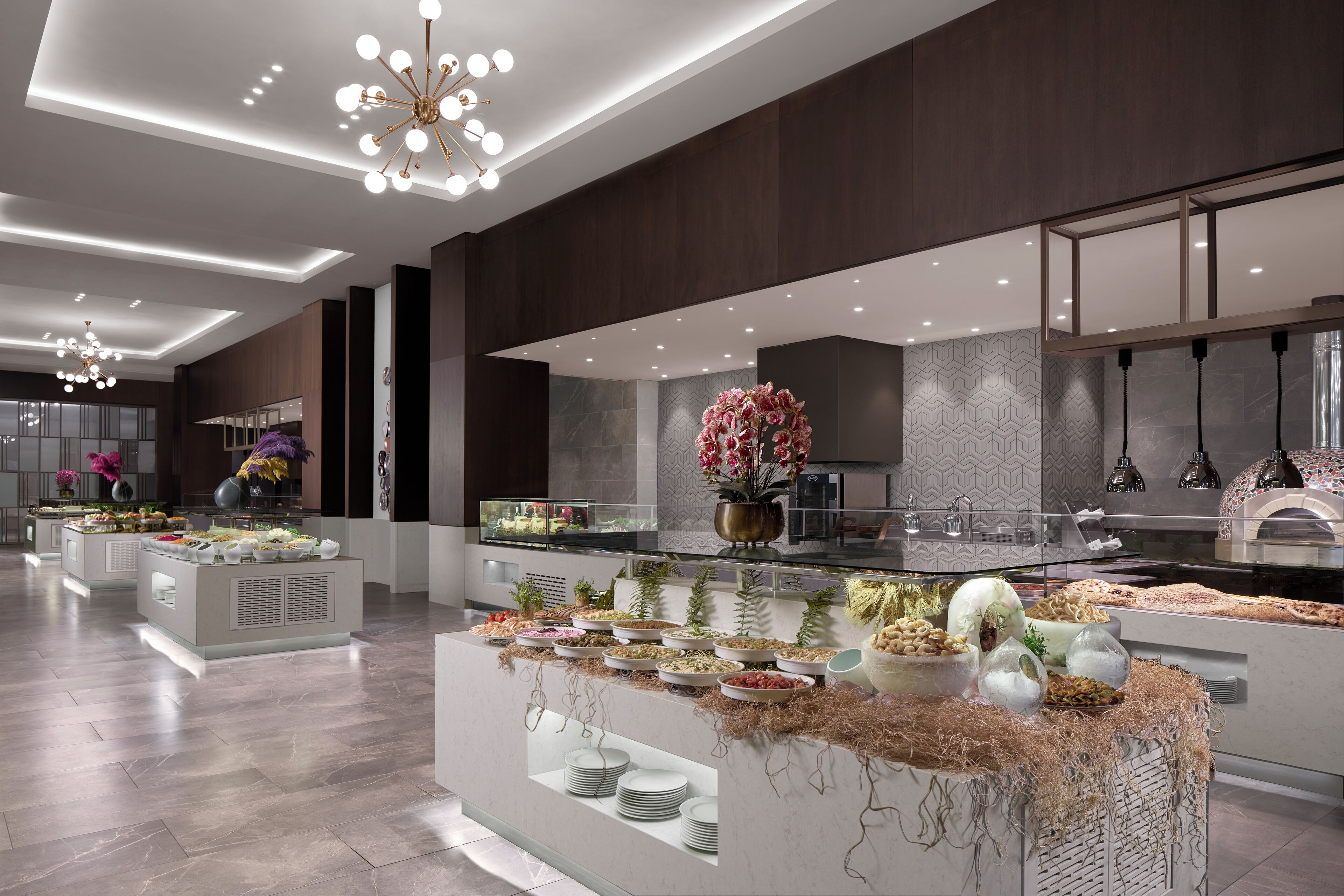 A modern hotel lobby with a buffet area, featuring a central island with various food items and a decorative centerpiece.