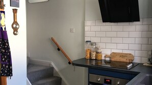 Una cocina moderna con una campana extractora negra, una lámpara colgante y una escalera de madera.