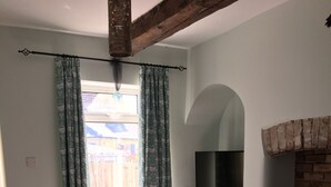 Una sala de estar con sofá, televisor, chimenea y ventana con cortinas.