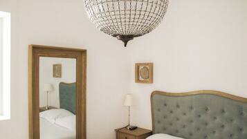 Un dormitorio con cama, mesita de noche, lámpara, espejo y candelabro.
