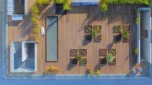 Vista aérea de una terraza en la azotea con varias zonas de estar, jardineras y una fuente central.