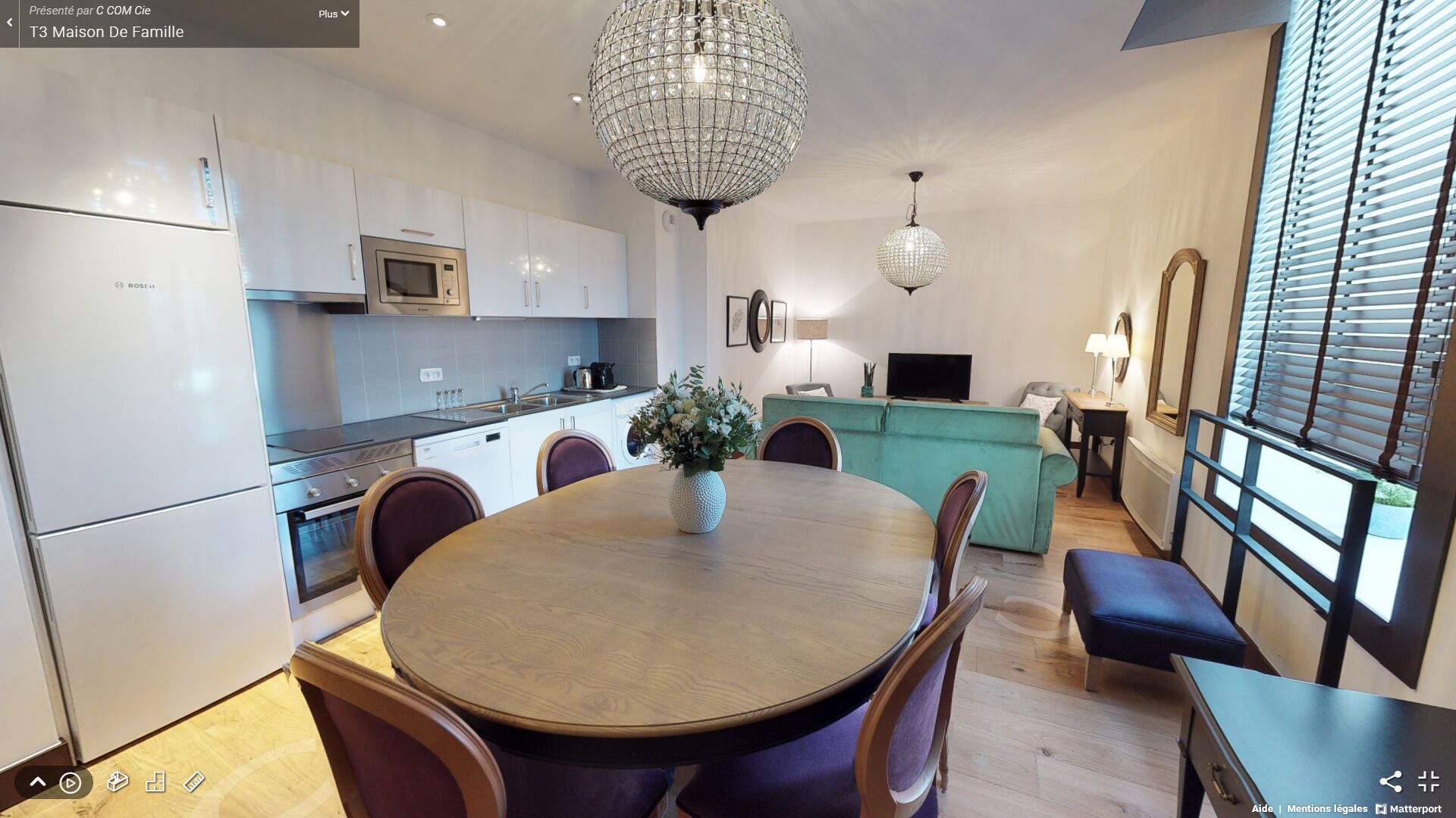 A modern kitchen with white cabinets, a Bosch microwave, and a chandelier.